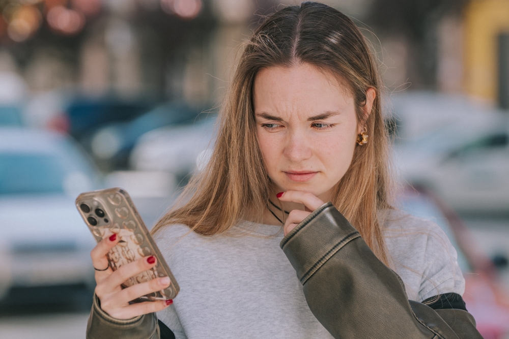 Ragazza che guarda il proprio smartphone con sospetto