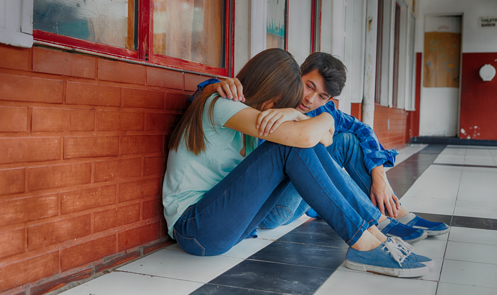 UN RAGAZZO CHE CONFORTA UNA RAGAZZA DOPO UN EPISODIO DI BULLISMO