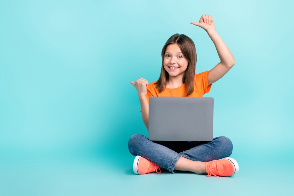 Bambina sorridente seduta con computer sulle gambe